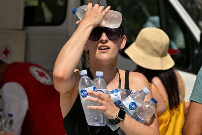 A woman cools off with water distributed by the Red Cross near the entrance of the Acropolis archeological site in Athens, Greece, in July 2023